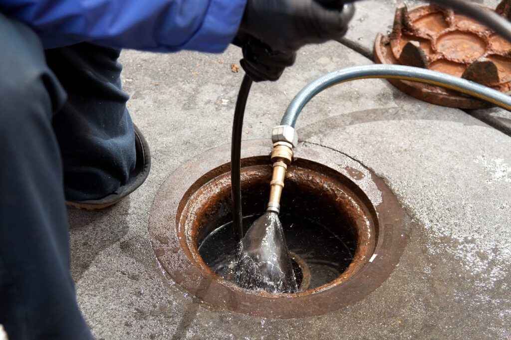 Plumber hydro jetting a sewer line through a manhole in Rancho Cucamonga