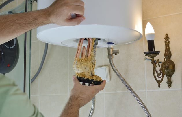 Technician removing mineral buildup from a water heater in Rancho Cucamonga