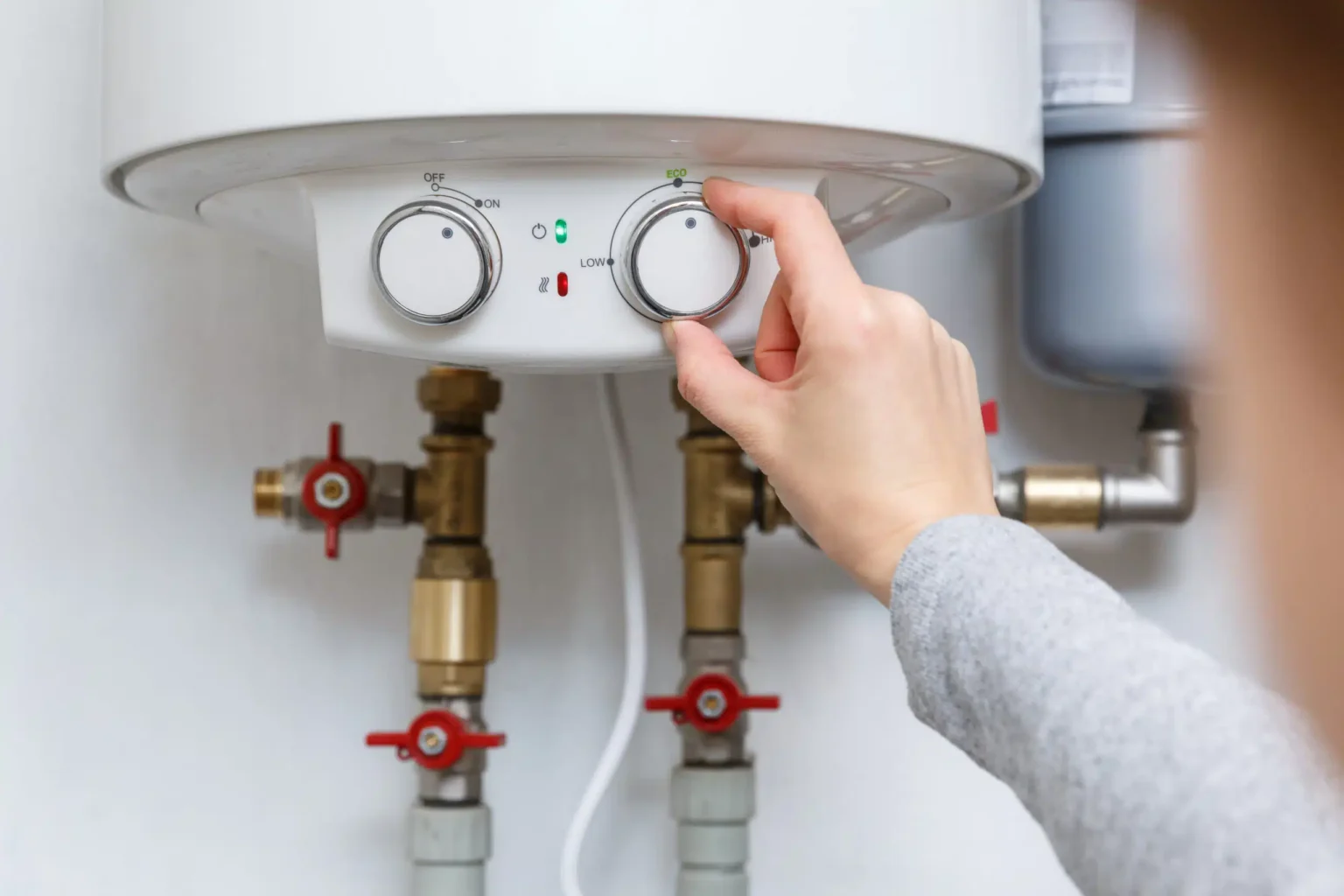 Homeowner adjusting the temperature controls on a water heater in Rancho Cucamonga
